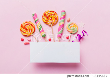 Flat lay holiday composition. Paper blank, lollipop, birthday decorations on Colored background. Top view, copy space for text 98345617