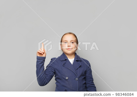 Smart little child school girl pointing up against white studio wall banner background  98346084