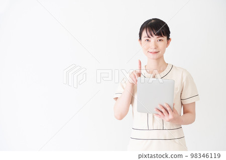 A woman at an esthetic and beauty clinic operating a tablet A woman at an esthetic and beauty clinic operating a tablet 98346119