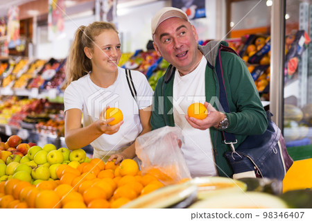 Father and his teenage daughter buying oranges Father and his teenage daughter buying oranges 98346407