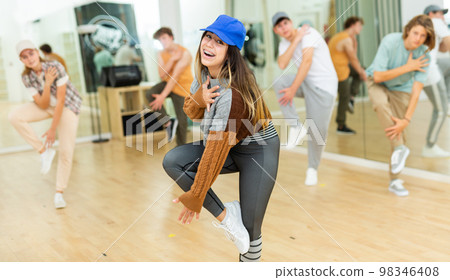 Cheerful hispanic teenage girl practicing hip-hop movements in studio 98346408
