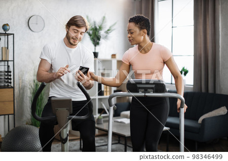 Attractive female and male working out on fitness at home. Attractive female and male working out on fitness at home. 98346499