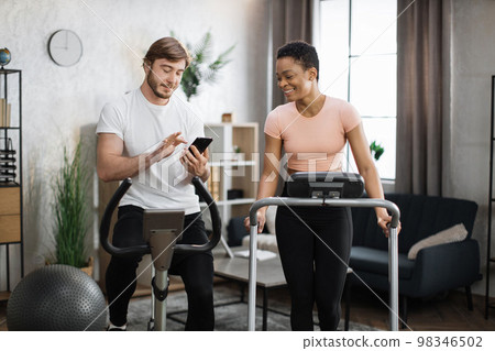 Attractive female and male working out on fitness at home. Attractive female and male working out on fitness at home. 98346502