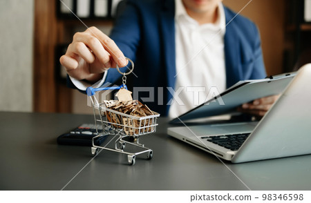 Model house is placed on a cart. Broker signs a sales agreement. agent, lease agreement, successful deal 98346598