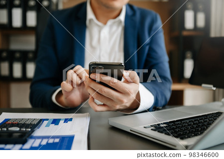 Businesswoman s hands typing on smartphone and  laptop keyboard in morning light computer, typing, online in office. 98346600