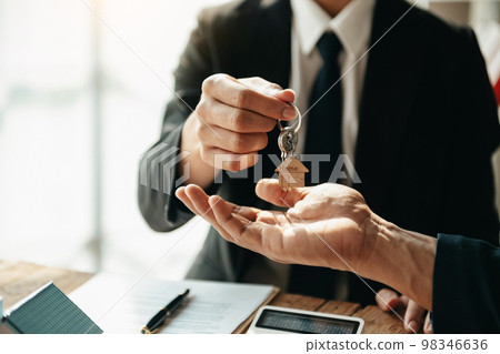 Buying a home or insurance deal, an insurance agent pointing a pen to those interested in renting a house, a contract, signing an Home buying agreement in office Buying a home or insurance deal, an insurance agent pointing a pen to those interested in renting a house, a contract, signing an Home buying agreement in office 98346636