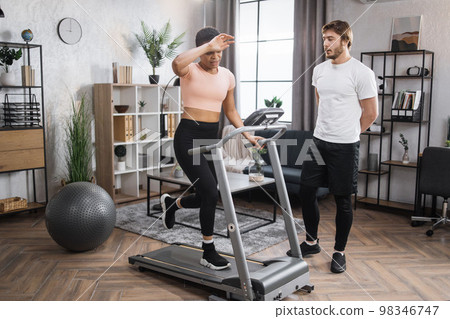 Portrait of focused young african female wearing sportswear and using treadmill 98346747