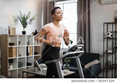Attractive young sports african american woman holding bottle with water working out Attractive young sports african american woman holding bottle with water working out 98347104