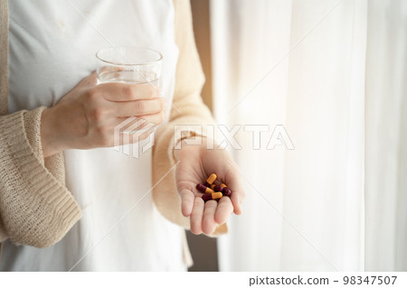 Depressed woman holding a glass of water, suffering from headaches, fighting stress with antidepressants, close-up view. Depressed woman holding a glass of water, suffering from headaches, fighting stress with antidepressants, close-up view. 98347507