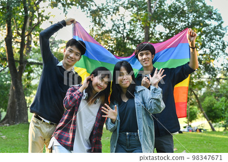 Group of young activist standing under pride rainbow flag, love symbol of LGBT community. Diversity and human rights concept 98347671
