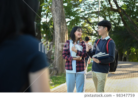 Two happy university student walking in campus, going to lesson and talking to each other. Youth lifestyle and friendship concept Two happy university student walking in campus, going to lesson and talking to each other. Youth lifestyle and friendship concept 98347759