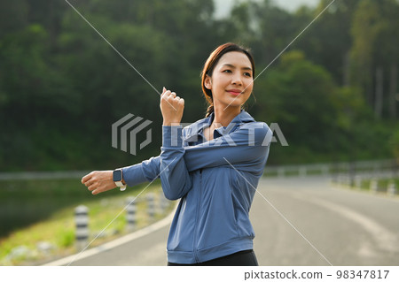 Sporty asian woman in sportswear stretching warming up her body before running in the green park Sporty asian woman in sportswear stretching warming up her body before running in the green park 98347817