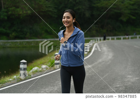 Sports woman listening to music and running outdoors in the morning. Fitness, sport and healthy lifestyle concept 98347885