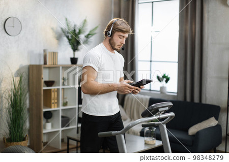 Bearded caucasian businessman in sportswear and headset training at home working with tablet Bearded caucasian businessman in sportswear and headset training at home working with tablet 98348279