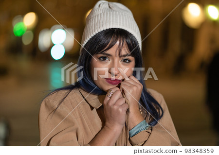 Young woman in warm clothes standing on street Young woman in warm clothes standing on street 98348359