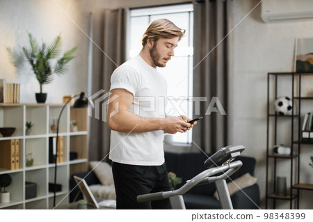 Attractive young sports caucasian man using phone while working out 98348399