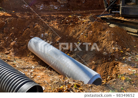 Worker laying sewage pipes in ground, preparing to put concrete pipes underground Worker laying sewage pipes in ground, preparing to put concrete pipes underground 98349652