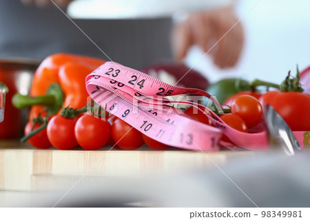Red tomatoes measuring tape and vegetables in kitchen Red tomatoes measuring tape and vegetables in kitchen 98349981