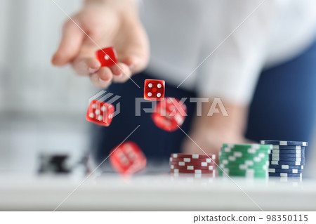 Player rolls dice on poker table closeup 98350115