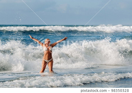 A girl with wet hair happily swims on the waves in the Atlantic Ocean.Tenerife.Spain A girl with wet hair happily swims on the waves in the Atlantic Ocean.Tenerife.Spain 98350328