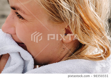 Close-up of a woman's face smeared in volcanic black sand on the beach Close-up of a woman's face smeared in volcanic black sand on the beach 98350331