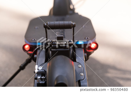 The back of the electric scooter with a foot rest on the asphalt background in sunny weather 98350480