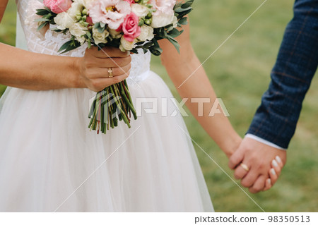 The bride's wedding bouquet of fresh pink flowers in her hand and holding hands with the groom. Wedding Details The bride's wedding bouquet of fresh pink flowers in her hand and holding hands with the groom. Wedding Details 98350513