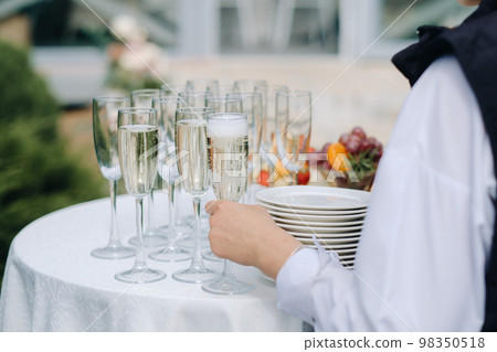 The guest takes a glass of champagne from the buffet table during a holiday or party 98350518
