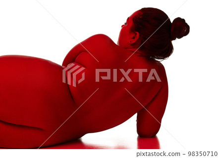 Portrait of naked nude woman posing over white background. Back view. Concept of beauty of overweight female body, bodypositive, fashion. Red light on skin 98350710