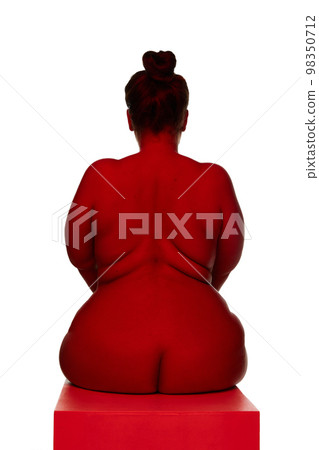 Portrait of naked nude woman posing over white background. Back view. Concept of beauty of overweight female body, bodypositive, fashion. Red light on skin 98350712