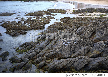 Detail of a sandy and rocky beach with calm waters. 98350811