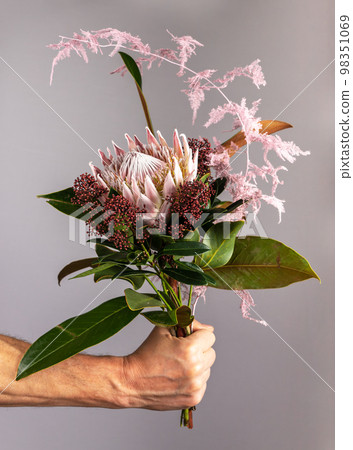 Flower bunch in men hand, spring romantic gift. Gentle gorgeous modern bouquet, posy of blossomed blooms, floral plants, leaf. High quality photo 98351069