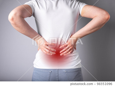 Backache. Woman suffering from lower back pain with red point closeup. Sport, household injury, chronic diseases. Sedentary lifestyle. Health care and medicine concept. High quality photo 98351096