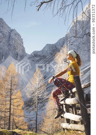 Vertical photo of young woman hiker enjoying the autumn sun up in the Alps Vertical photo of young woman hiker enjoying the autumn sun up in the Alps 98351372