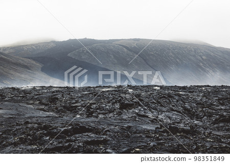 Dramatic view of still hot lava rocks and steam rising from the hot grounds Dramatic view of still hot lava rocks and steam rising from the hot grounds 98351849