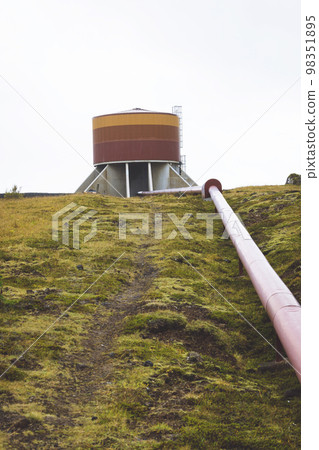 Vertical photo - red tube filled with hot water going up the green hill in Iceland Vertical photo - red tube filled with hot water going up the green hill in Iceland 98351895