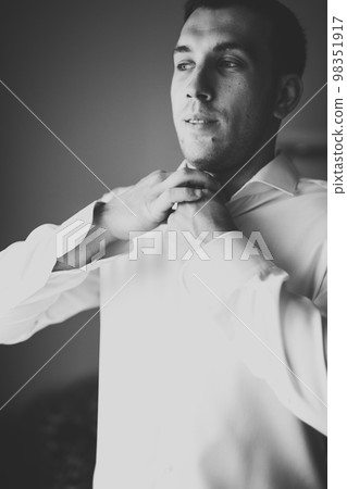 Grooms morning preparation. Handsome man getting dressed and preparing for the wedding Grooms morning preparation. Handsome man getting dressed and preparing for the wedding 98351917