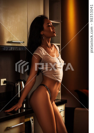 Portrait of asian beautiful girl in wet t-shirt in the kitchen Portrait of asian beautiful girl in wet t-shirt in the kitchen 98353041