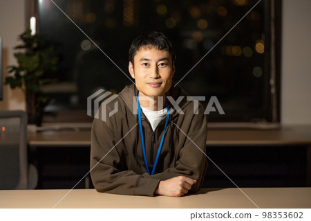 A man in his 30s looking at the camera in the office at night A man in his 30s looking at the camera in the office at night 98353602