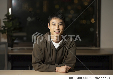 一個 30 多歲的男人晚上在辦公室裡看著相機 98353604