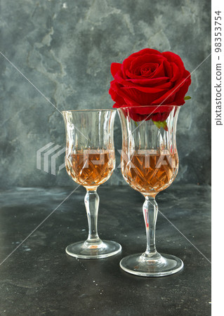 Close up two glasses of liquor and a rose on a black background. 98353754