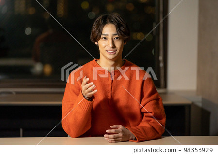 一個 20 多歲的男人看著鏡頭，夜間辦公室圖像 98353929