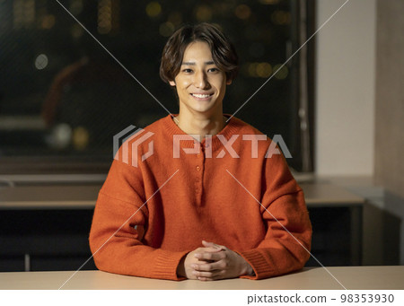 一個 20 多歲的男人看著鏡頭，夜間辦公室圖像 98353930