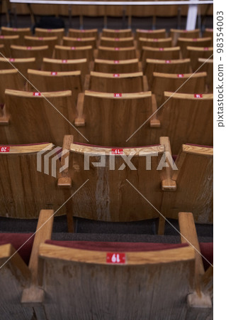Chairs in a row for the audience. The concept of the cultural environment. Wooden and symmetrical . Empty seats. High quality photo Chairs in a row for the audience. The concept of the cultural environment. Wooden and symmetrical . Empty seats. High quality photo 98354003