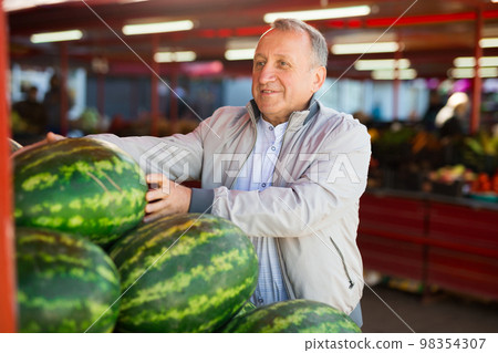 Man choosing watermelons in fruit shop Man choosing watermelons in fruit shop 98354307