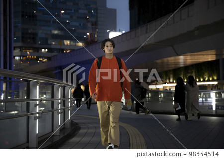 Young man walking in the night city 98354514
