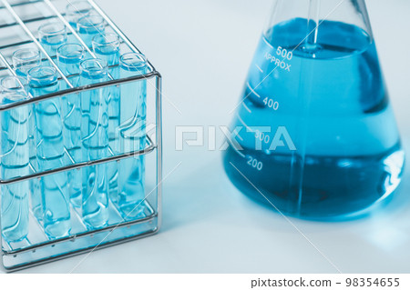 Test tubes and erlenmeyer flask filled with blue sample chemicals in chemistry science laboratory. Glassware in medical research. Scientific lab for Biotechnology. Test tubes and erlenmeyer flask filled with blue sample chemicals in chemistry science laboratory. Glassware in medical research. Scientific lab for Biotechnology. 98354655