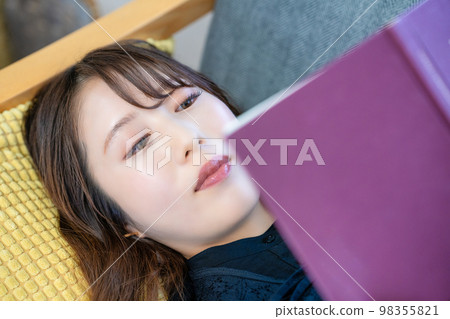 Woman lying on the couch and reading Woman lying on the couch and reading 98355821