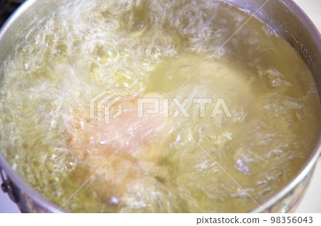A picture of ham being boiled in a pot of water 98356043