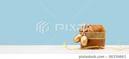 Happy Easter banner. Italian Easter Decorated Panettone and golden eggs on white table and festive ribbon. Wide banner on blue. Traditional bakery. Christianity Happy Easter banner. Italian Easter Decorated Panettone and golden eggs on white table and festive ribbon. Wide banner on blue. Traditional bakery. Christianity 98356663